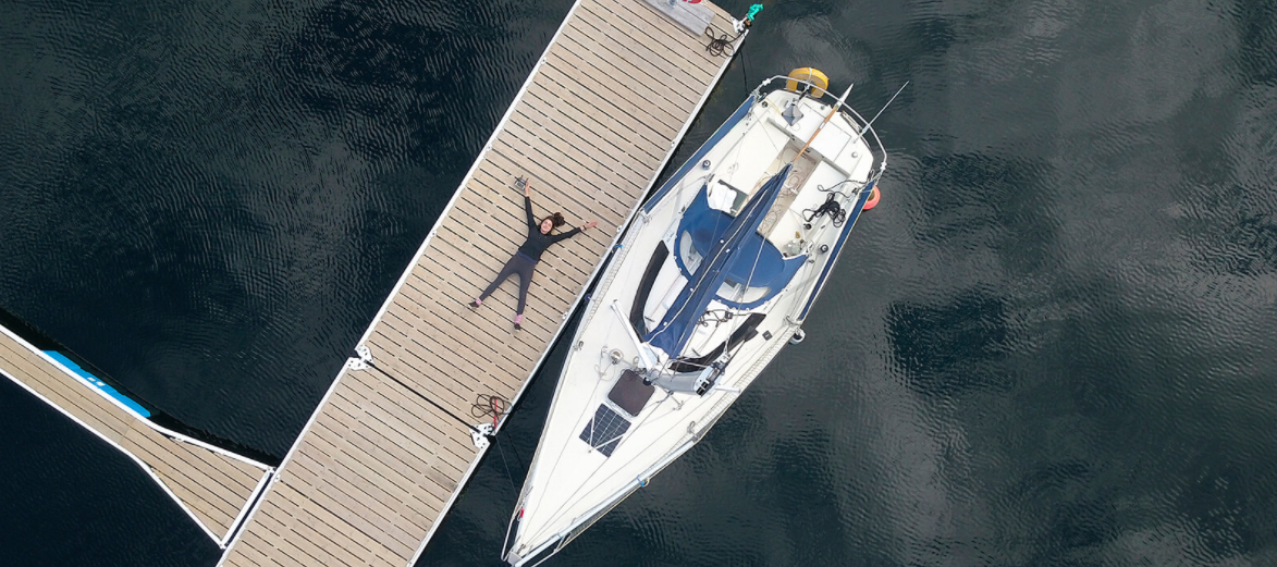 Tamara está deitada em um deck de madeira, no porto, ao lado de seu barco