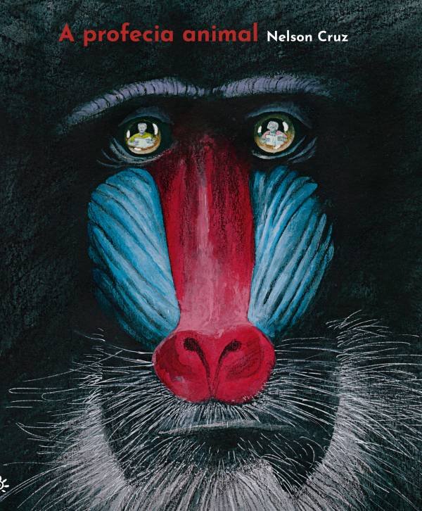 Capa do livro A profecia animal, de Nelson Cruz. A imagem mostra em close o rosto de um mandril, com destaque para suas cores vivas: o nariz vermelho vibrante e as laterais do rosto em azul. O fundo é escuro, o que realça ainda mais os traços faciais do animal. Nos olhos do mandril, vê-se o reflexo de do autor, desenhando. No canto superior esquerdo, em letras vermelhas e brancas, está o título do livro e o nome do autor: “A profecia animal — Nelson Cruz”.